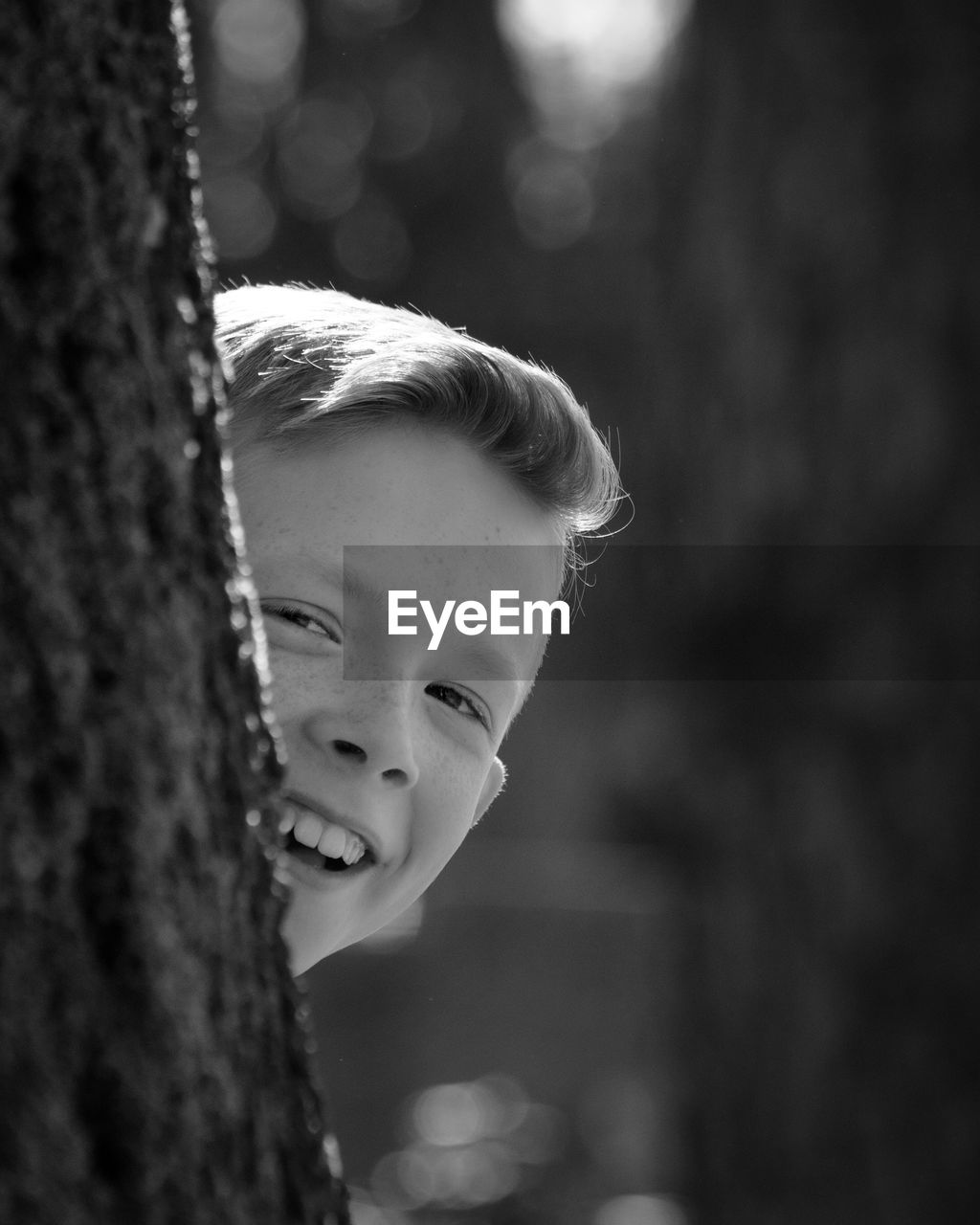 Close-up of boy behind tree