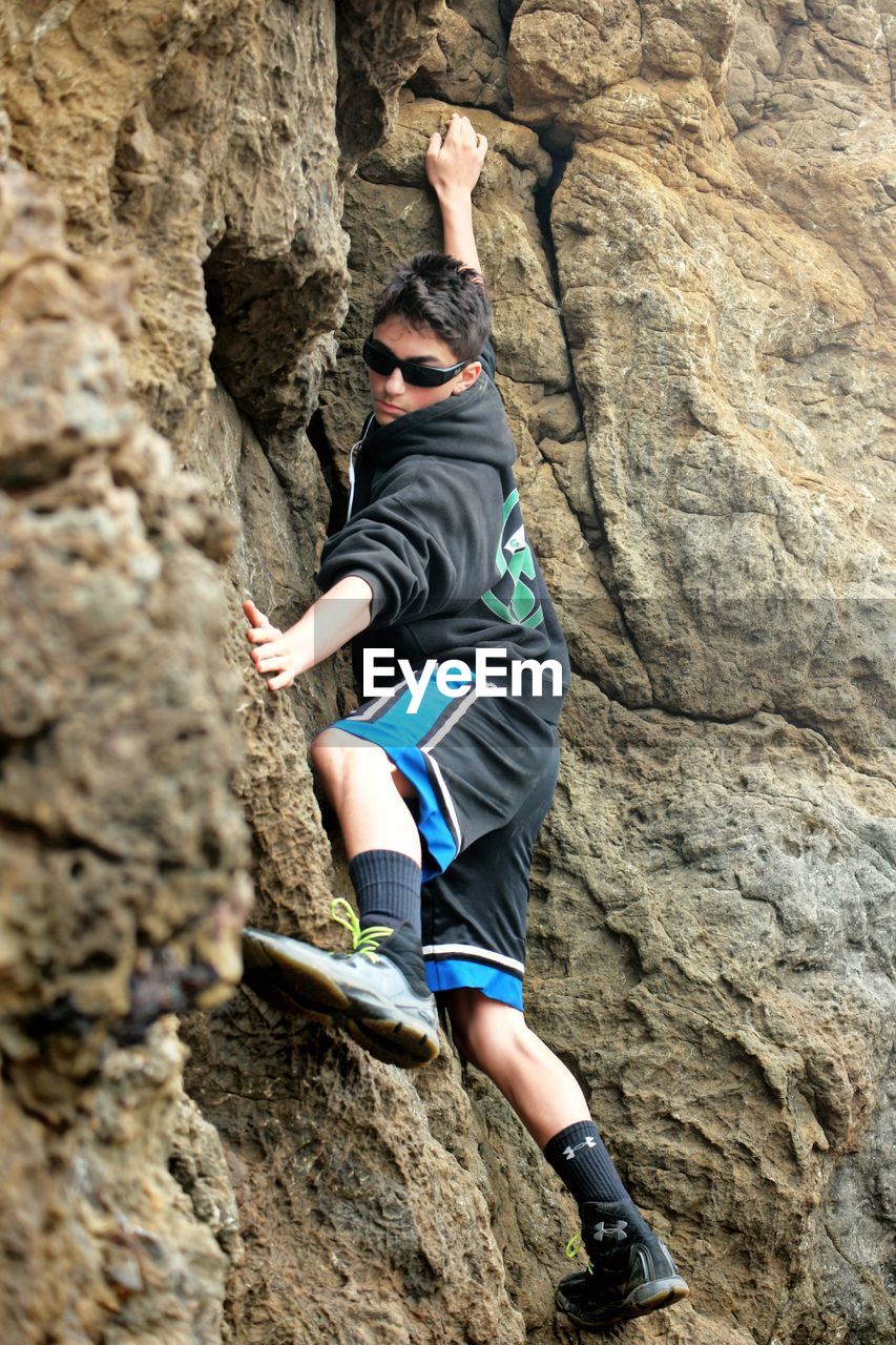 Teenage boy climbing on rock formation