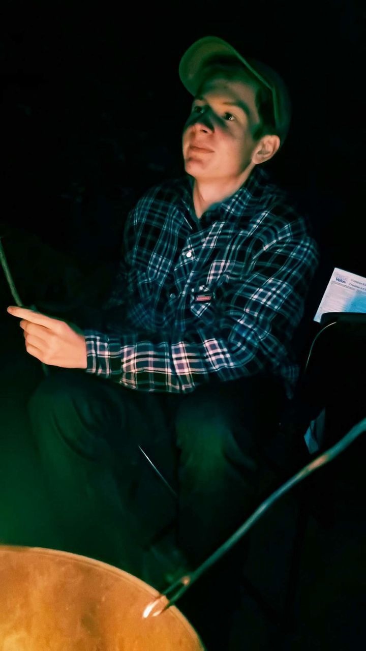 Smiling teenage boy looking away in dark tent