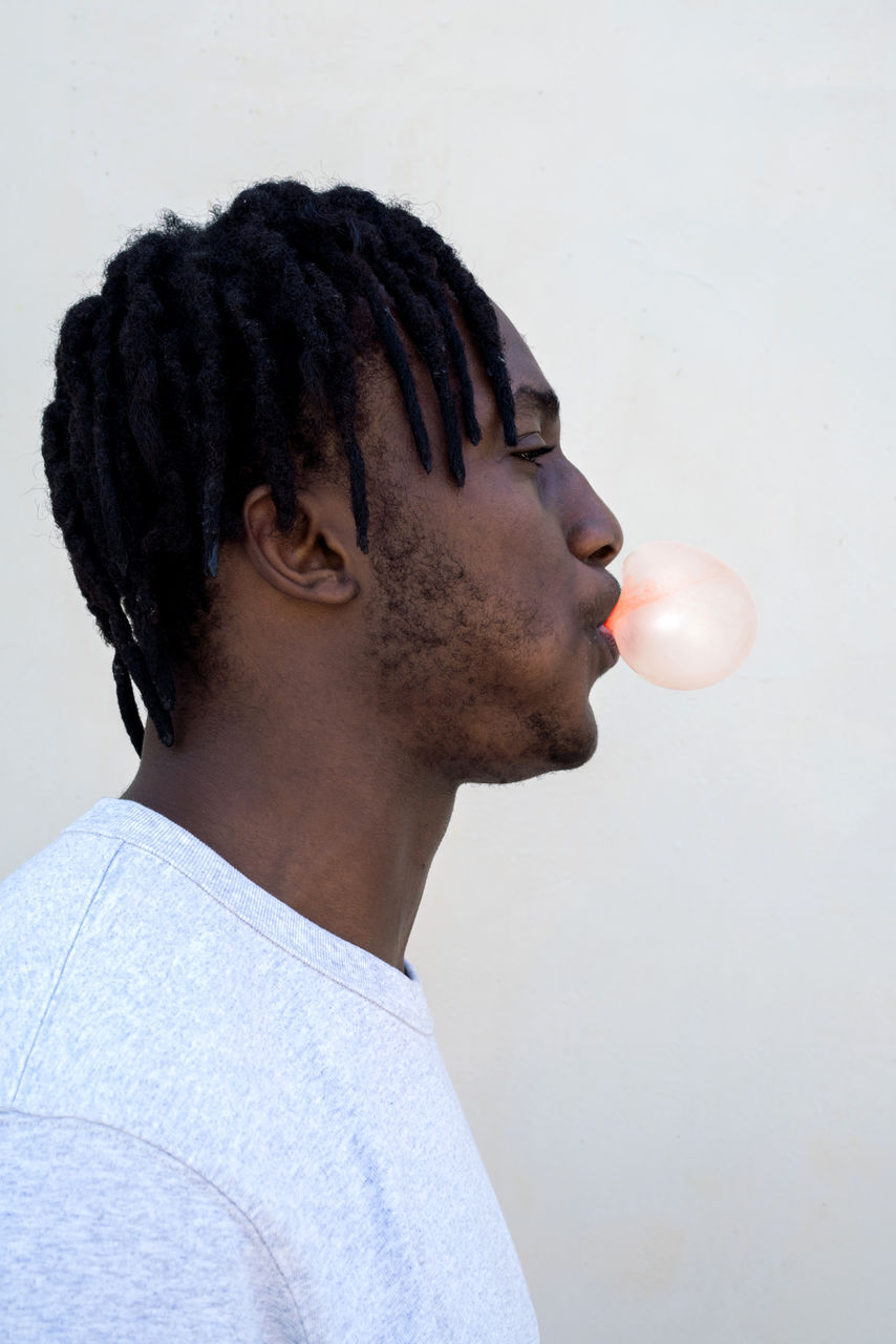 Black man making bubble with a chewing gum