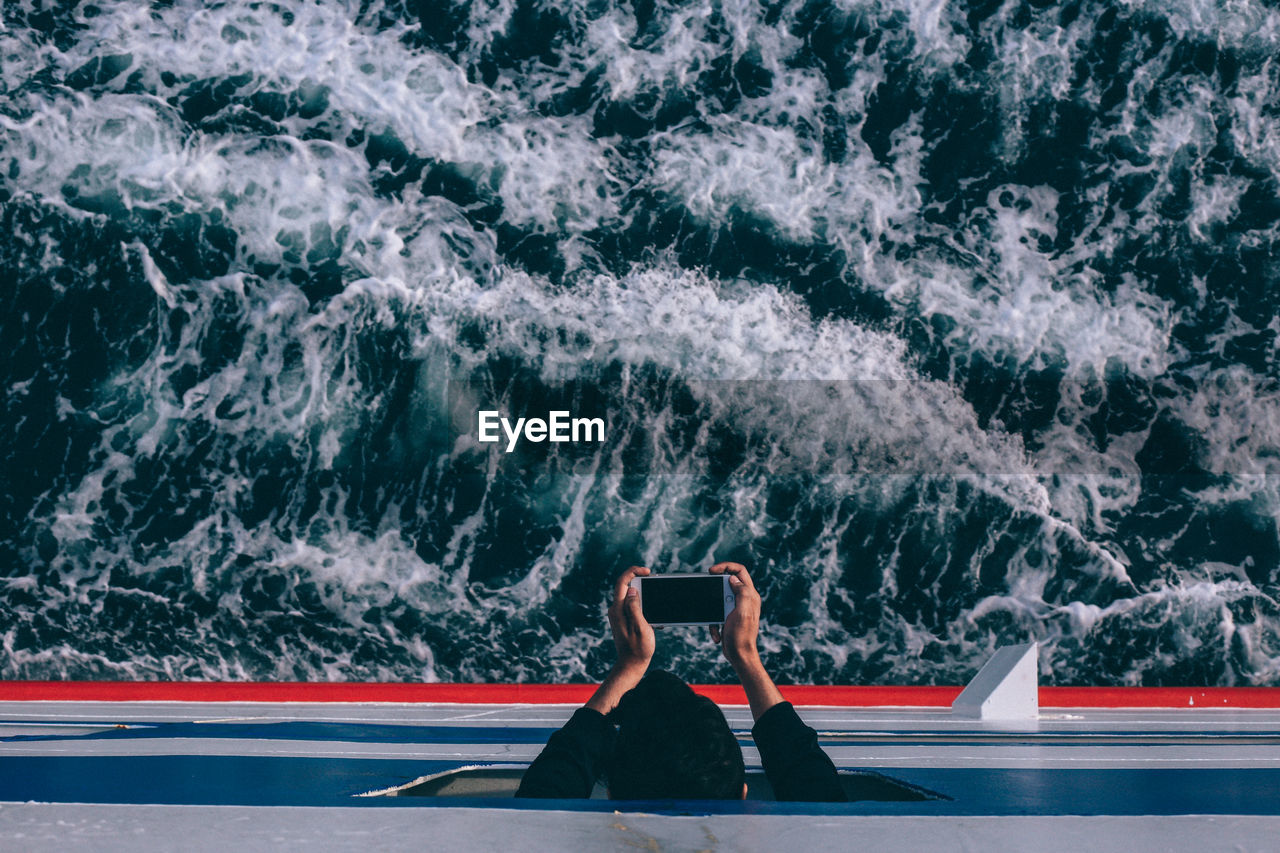 Directly above shot of man photographing in ship on sea