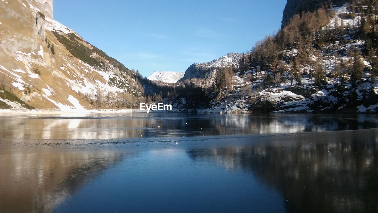 Scenic view of lake and mountains against blue sky