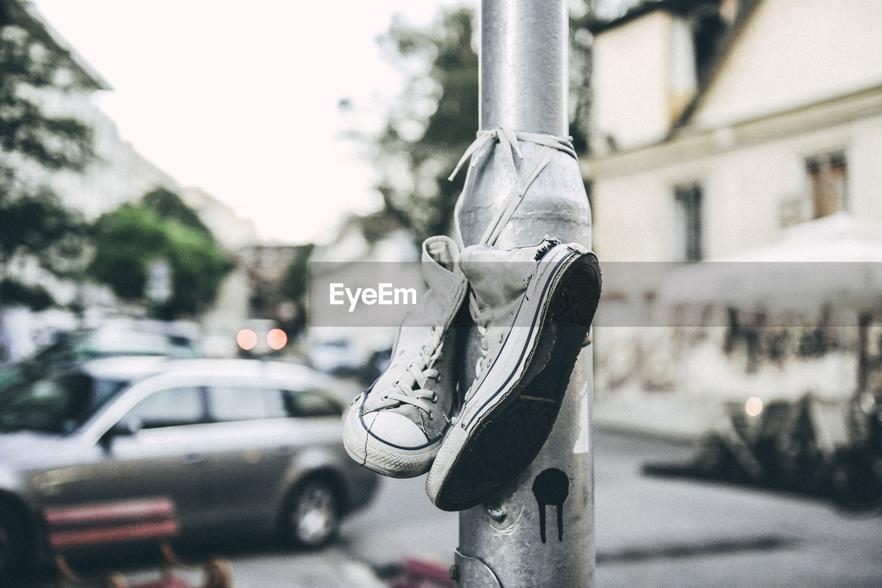 Close-up of canvas shoes tied on light pole at street
