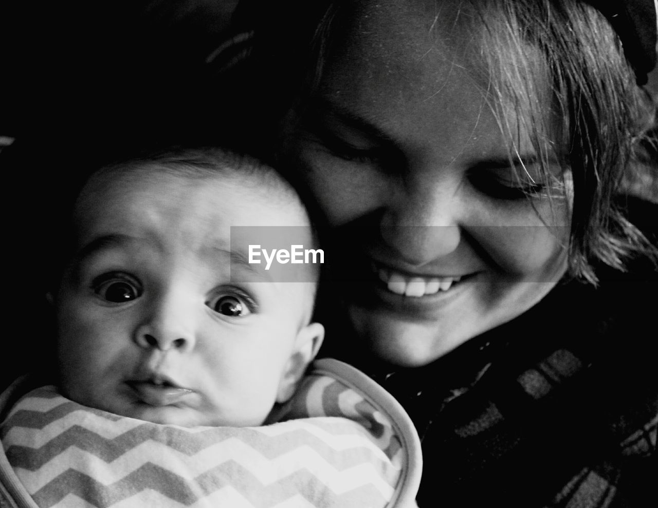 Close-up of smiling mother with surprised baby