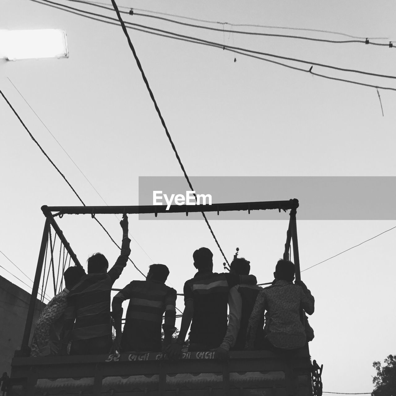 Low angle view of friends traveling in truck against clear sky