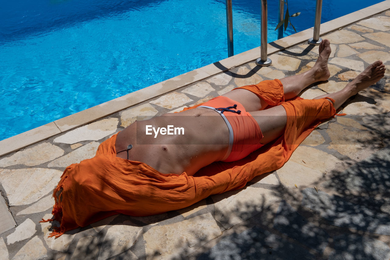 HIGH ANGLE VIEW OF PERSON RELAXING ON SWIMMING POOL