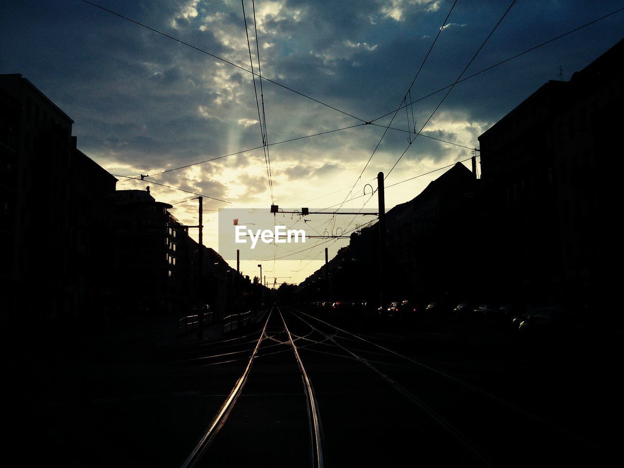 RAILROAD TRACKS AGAINST CLOUDY SKY