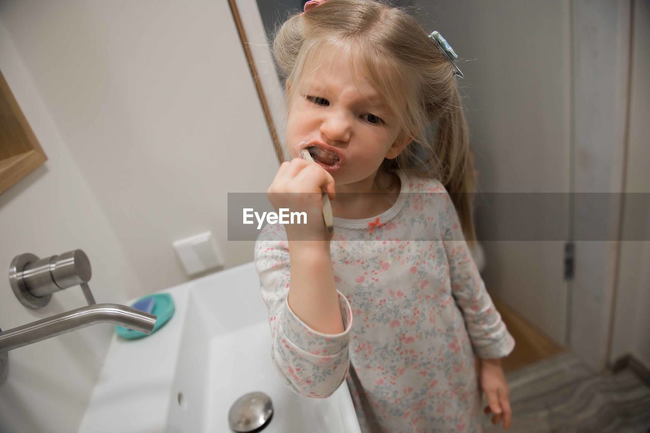 Girl brushing teeth in bathroom at home