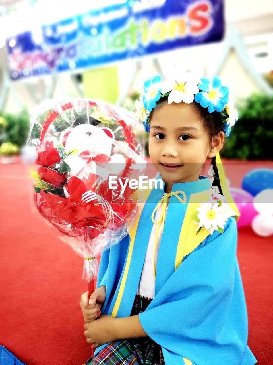 Portrait of cute girl holding toy while sitting on stage in school