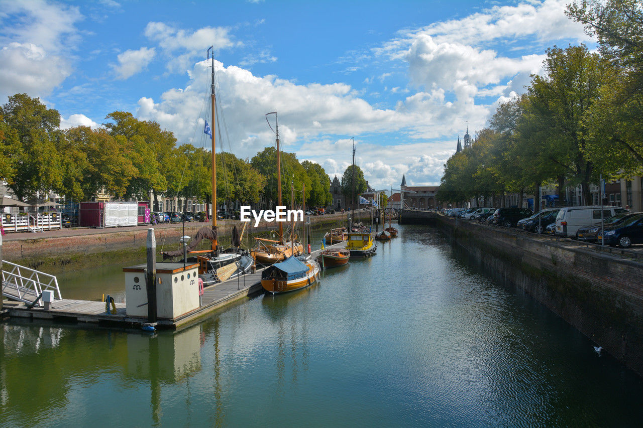 boats moored in canal against sky