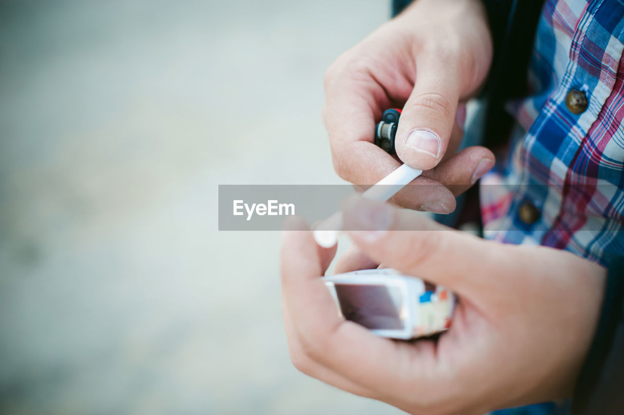 Close-up of man hand holding cigarette and lighter