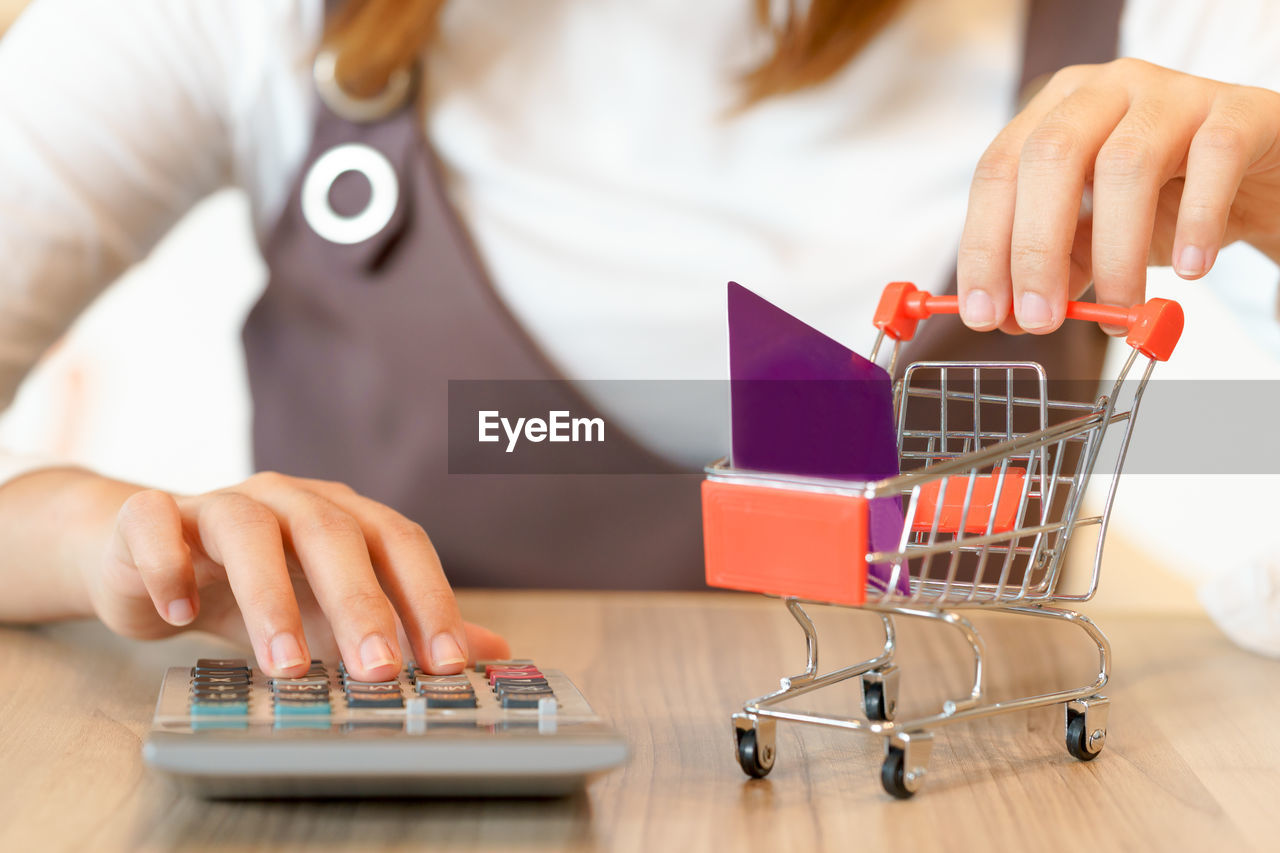 Midsection of woman holding shopping cart at table