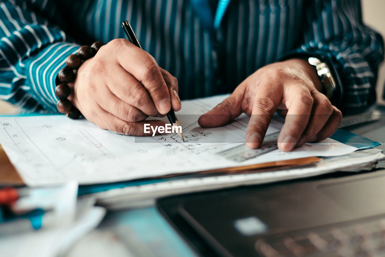 Midsection of man drawing on paper over table