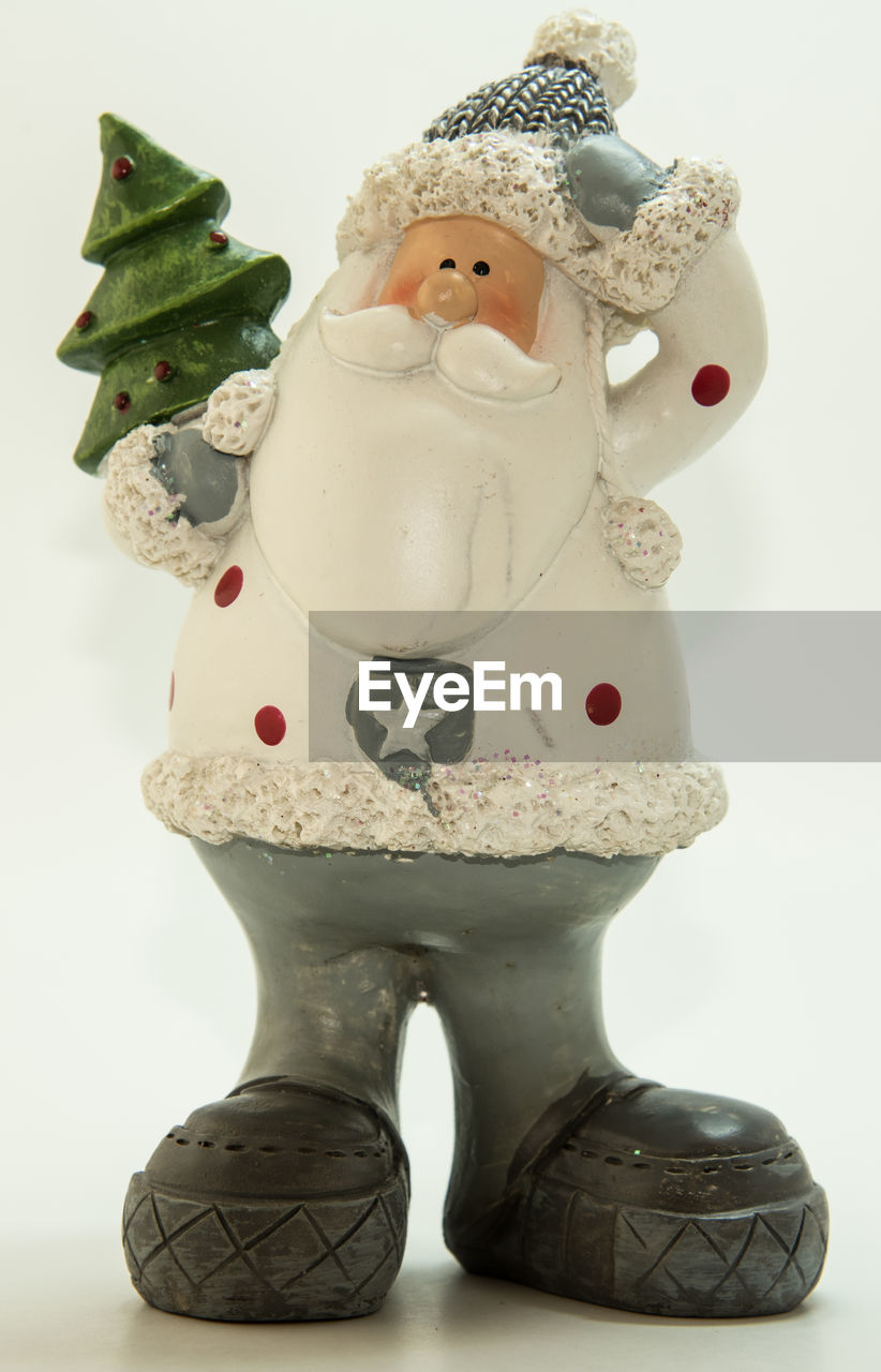 Close-up of wooden santa claus on table against white background