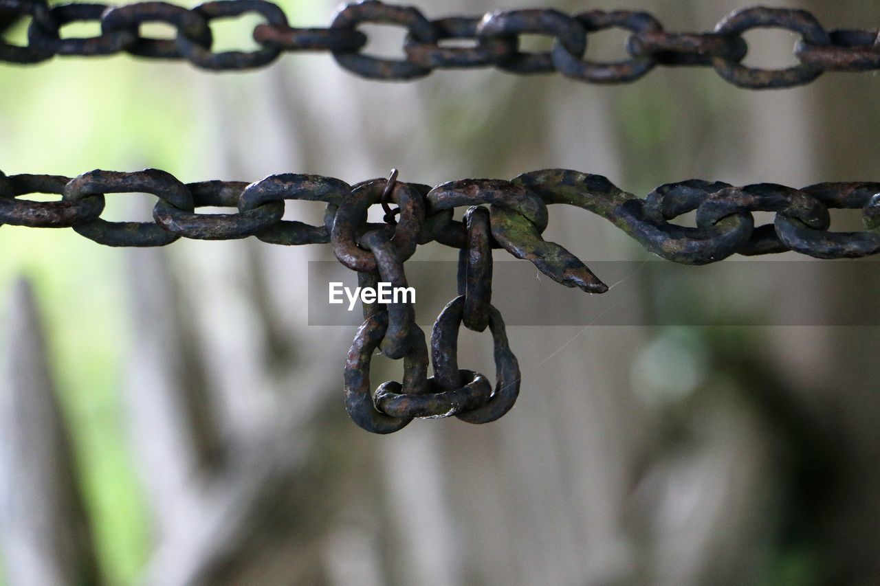 CLOSE-UP OF RUSTY CHAIN ON METAL FENCE