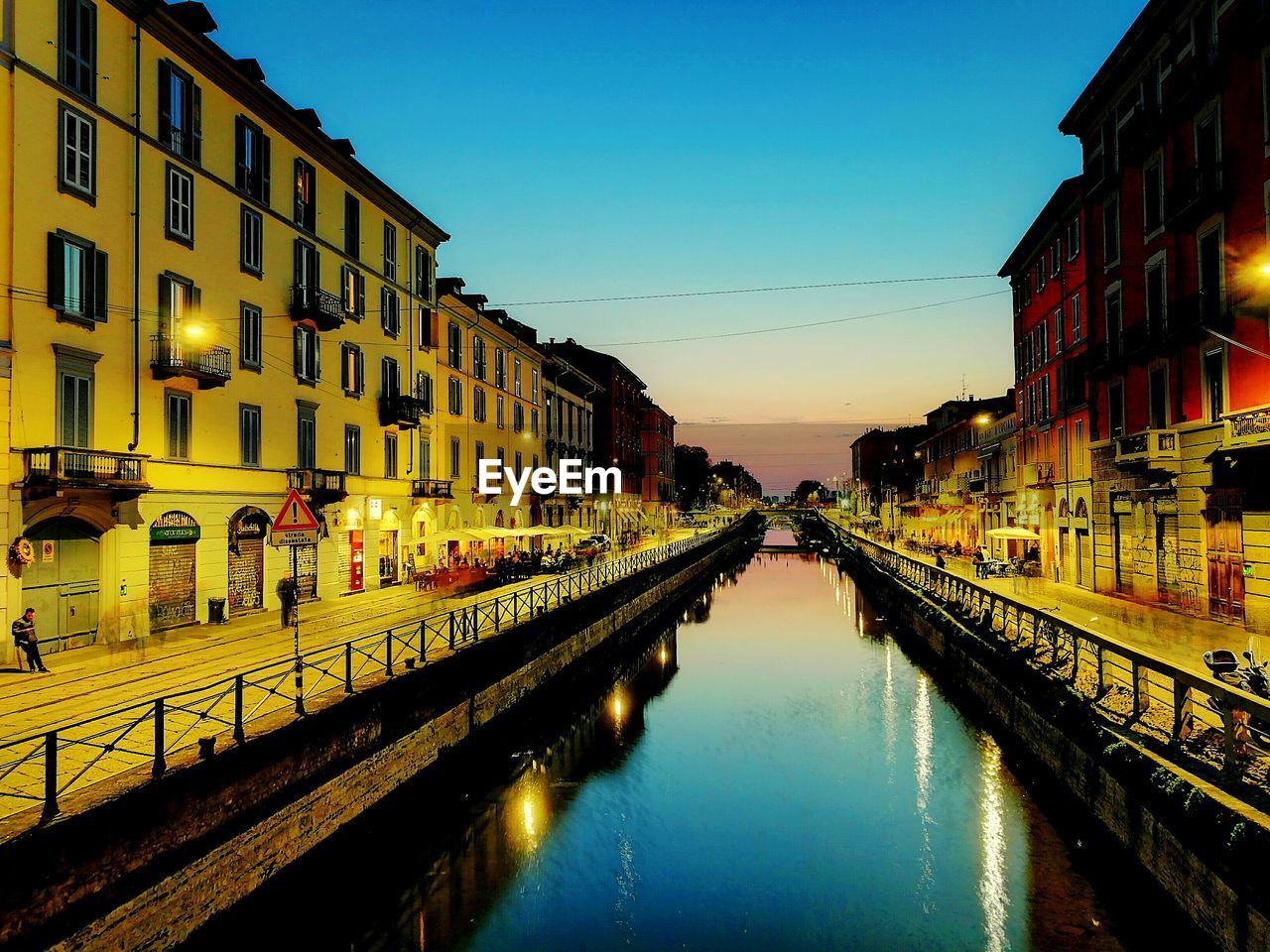 CANAL AMIDST ILLUMINATED CITY AGAINST SKY