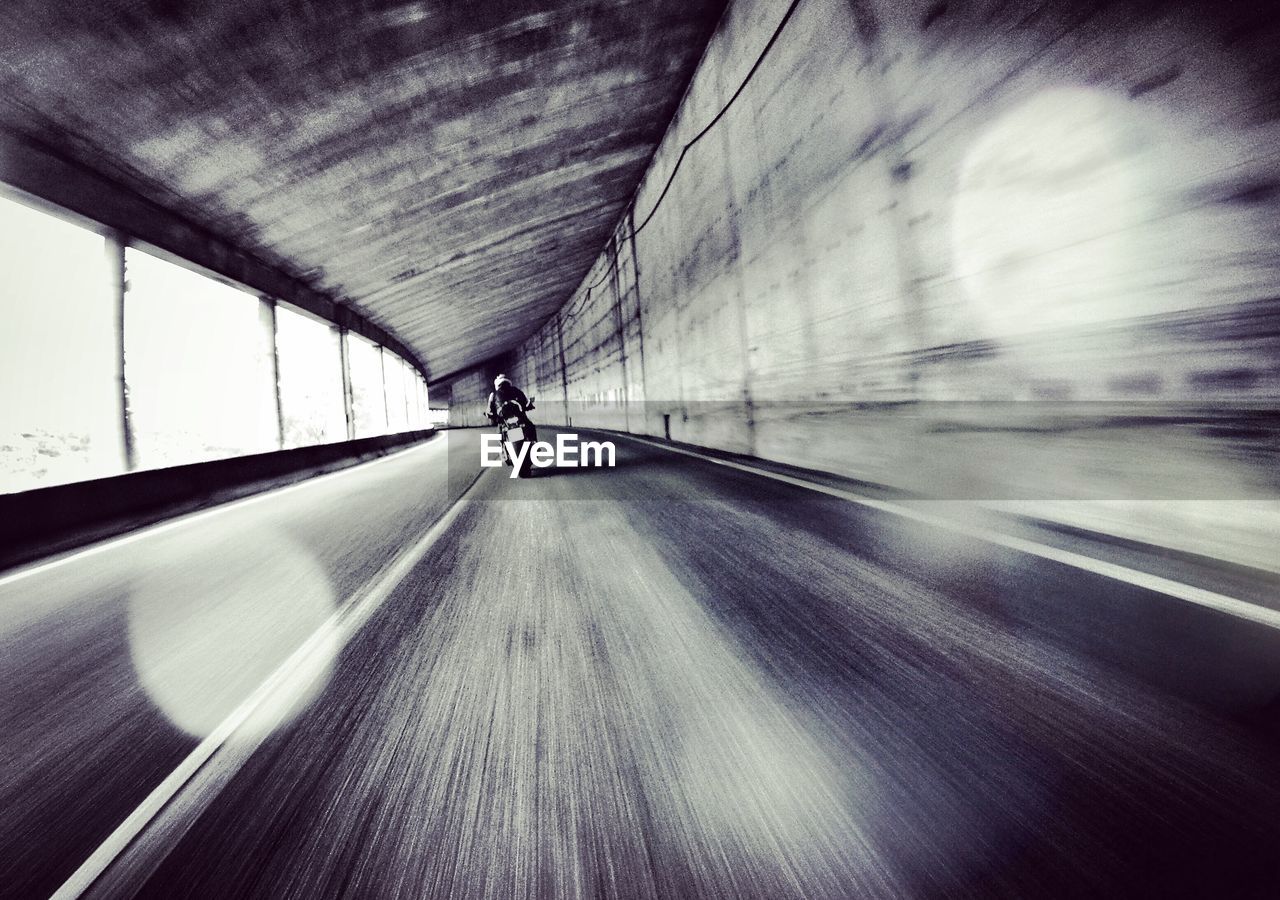 Blurred motion of person riding motorcycle in tunnel