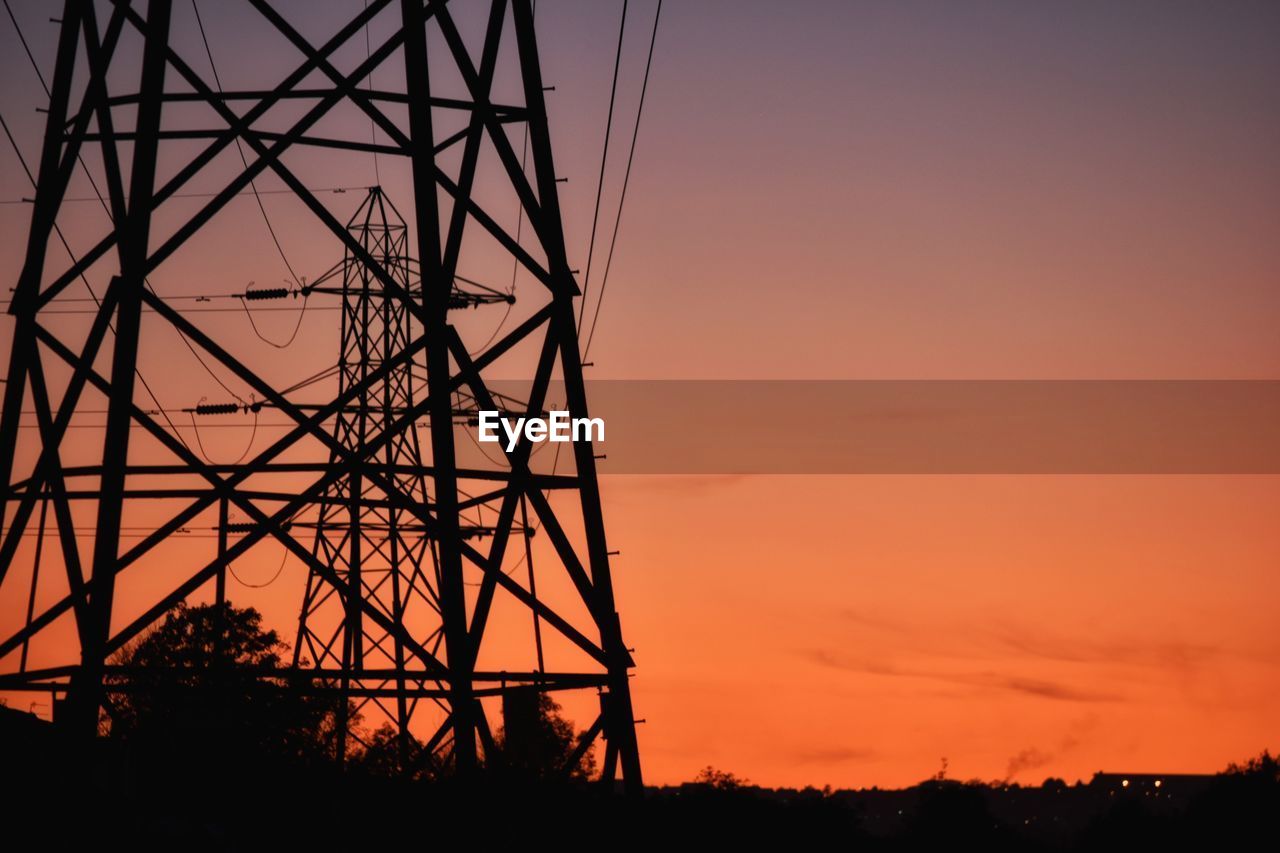 Silhouette electricity pylons against sky during sunset