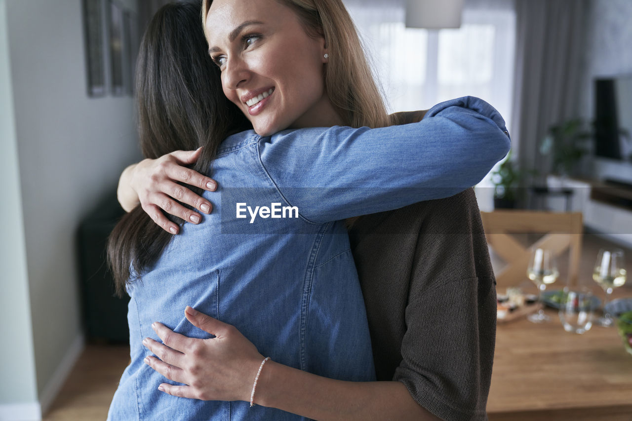 Female friends embracing at home