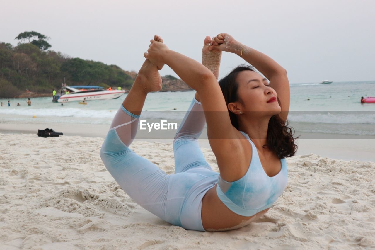 Young woman doing yoga at beach