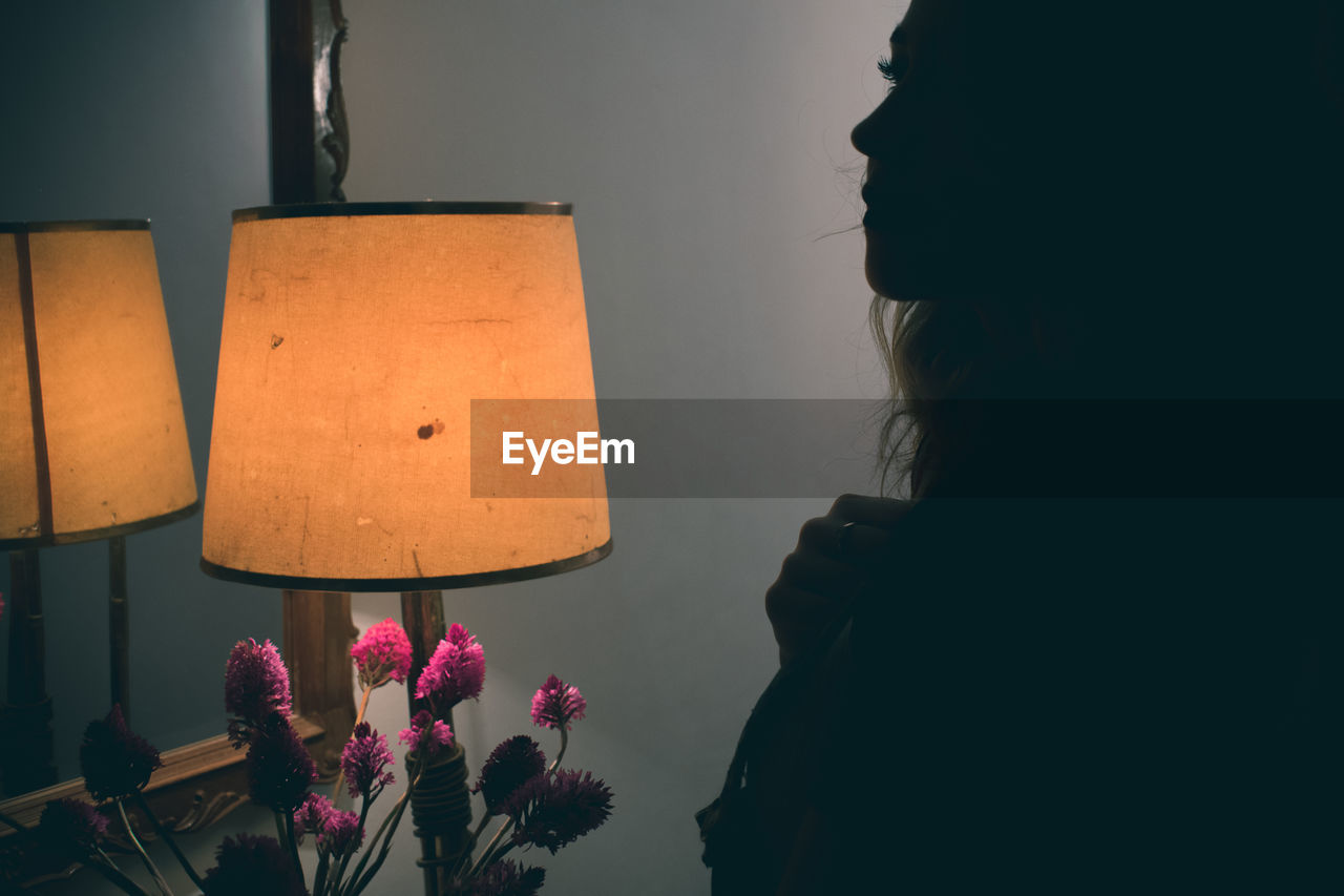 Silhouette woman by illuminated lamp at home