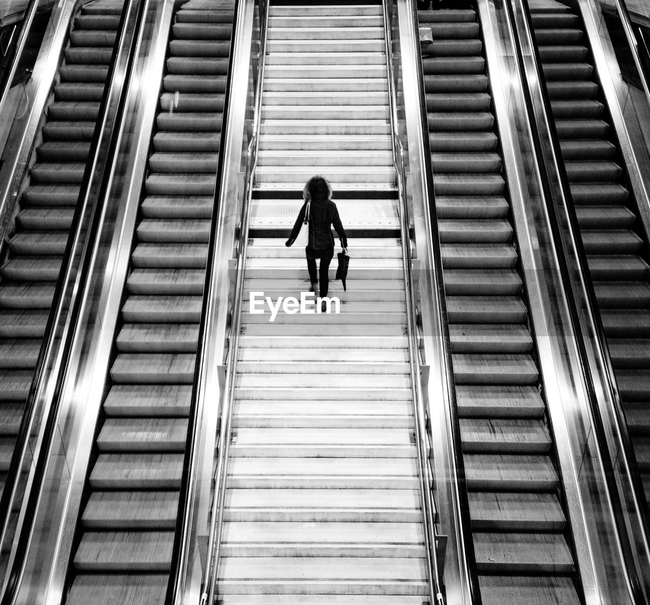 Rear view of woman walking on escalator