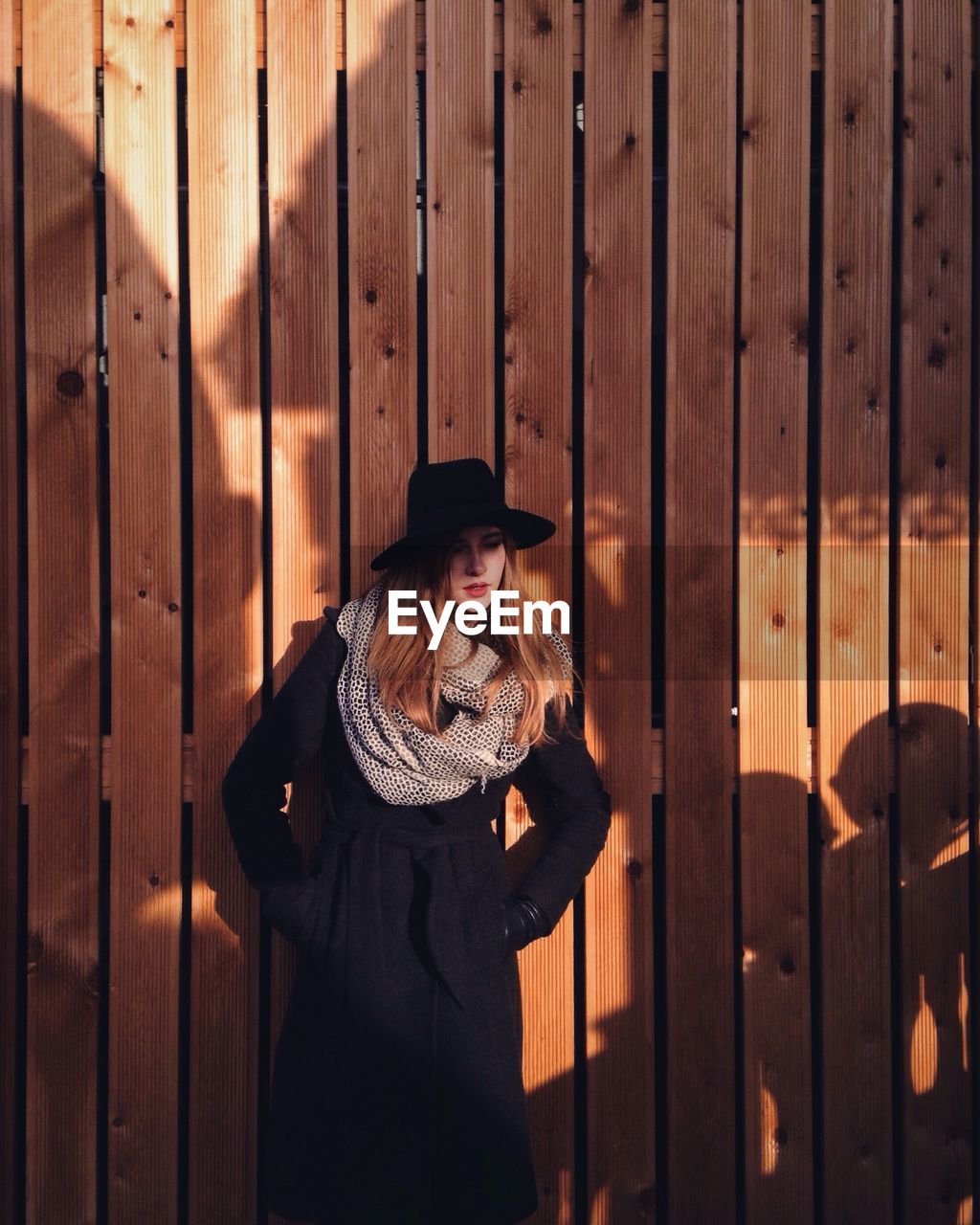 Girl looking away while standing against wall