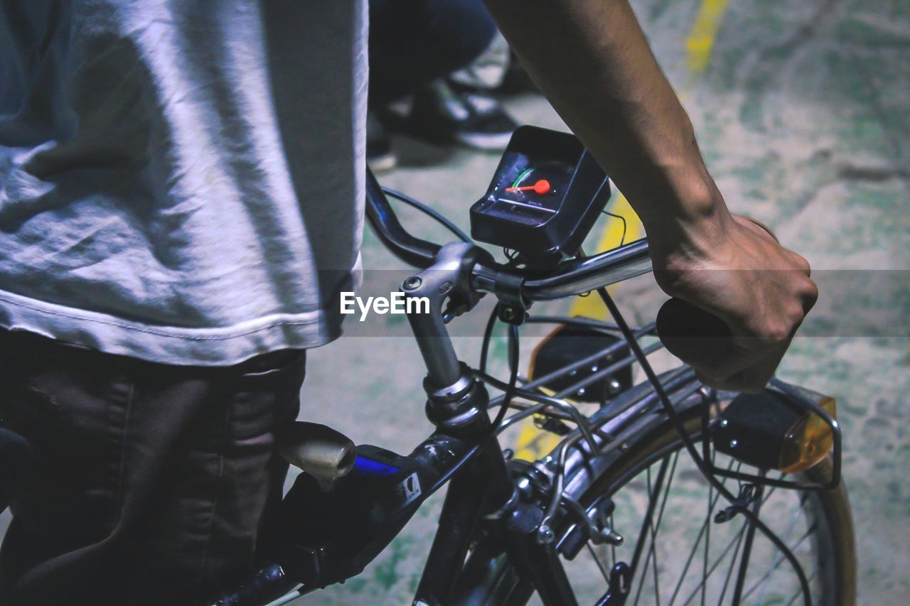 Midsection of man riding bicycle on road