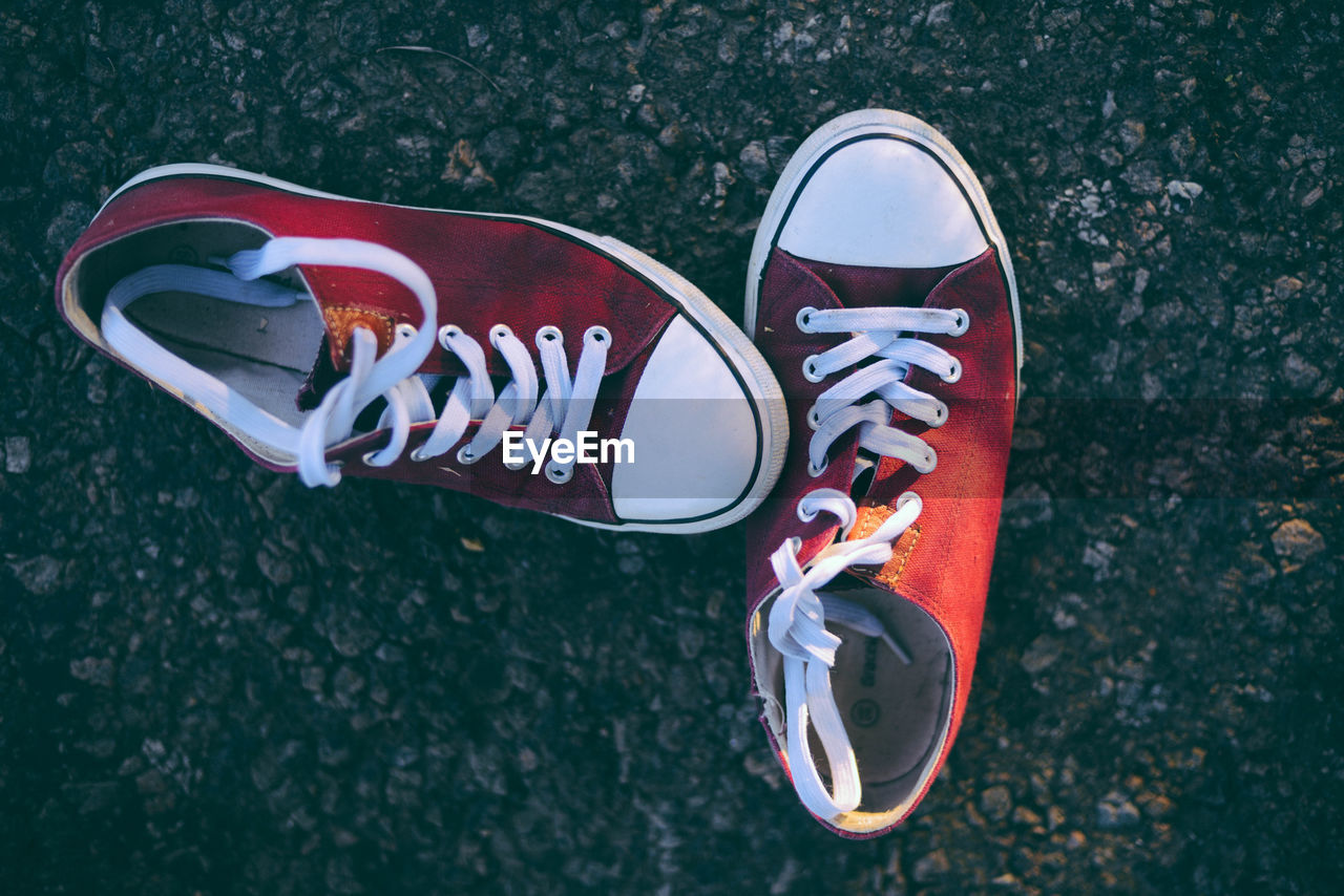 HIGH ANGLE VIEW OF CANVAS SHOES ON ROAD