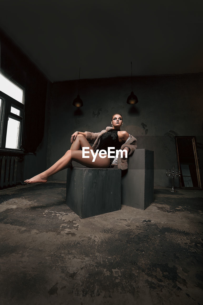 Young woman looking away while sitting on seat at home