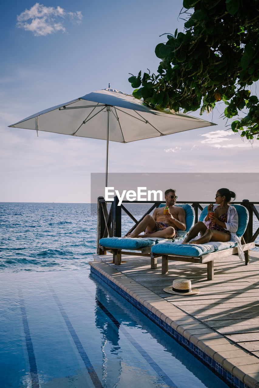 People sitting near pool against sky