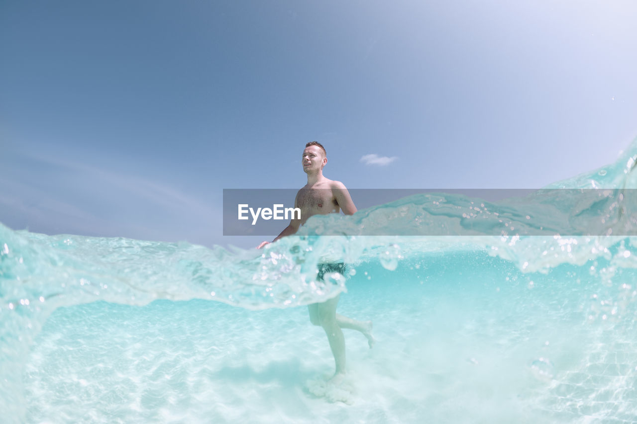 Man walking on sand seabed of beautiful turquoise sea. tourist enjoying beach holiday.