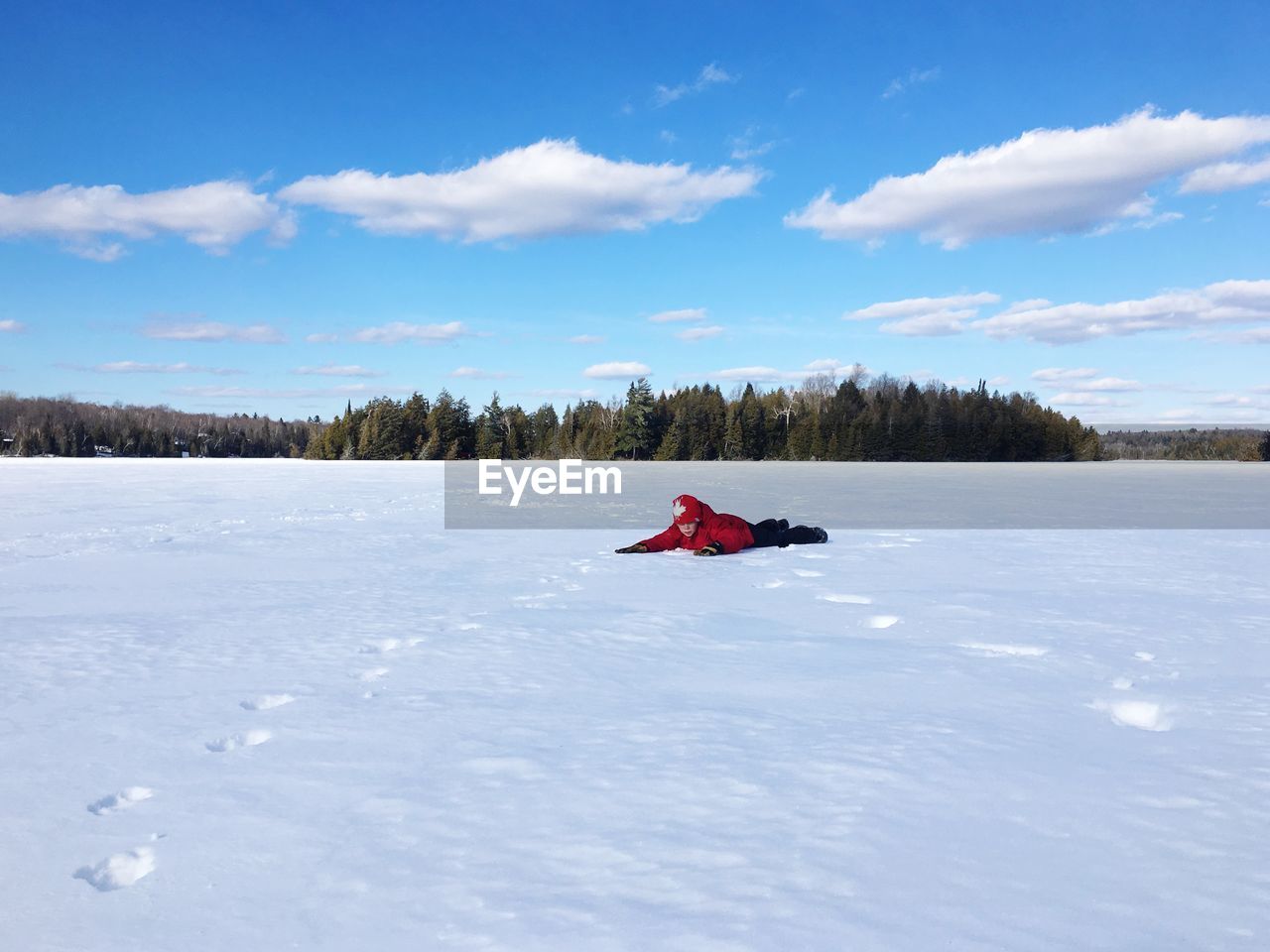 Full length of boy lying on snowy field