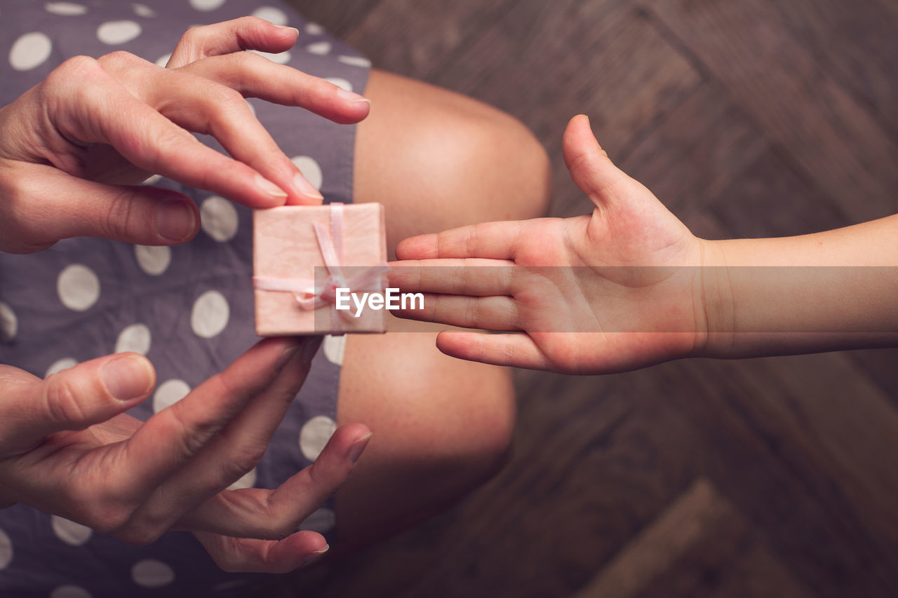 Cropped image of woman giving gift box to child