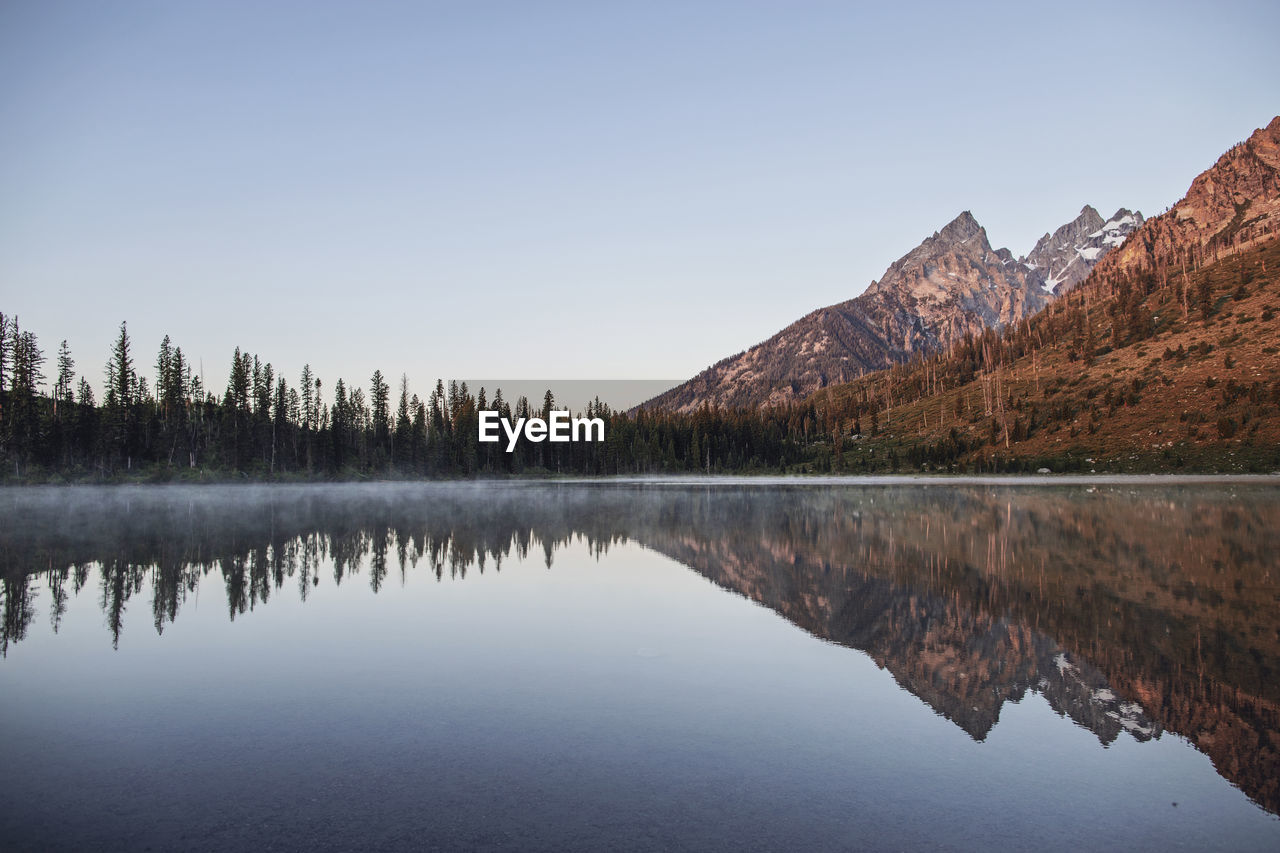 Tetons reflected in the still waters of string lake at sunrise