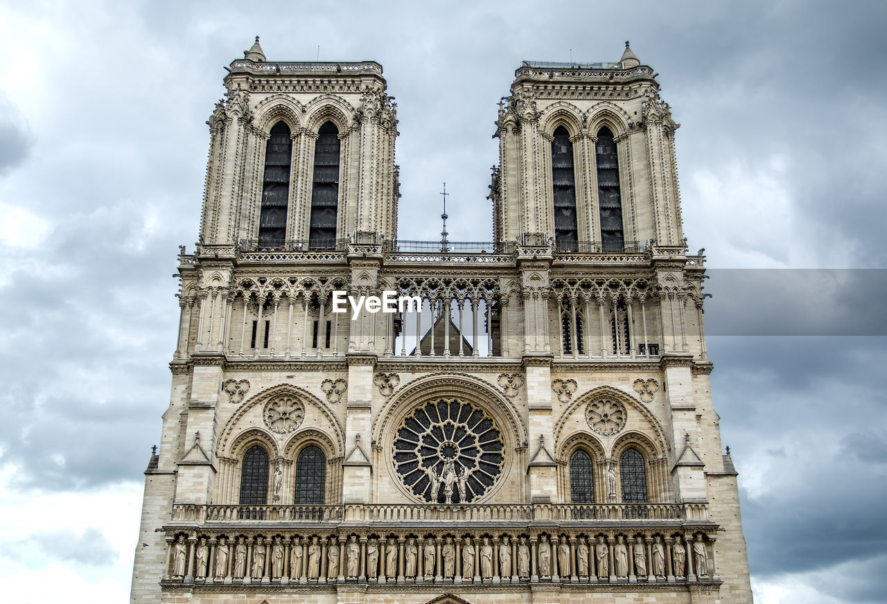 Low angel view of notre dame de paris against cloudy sky