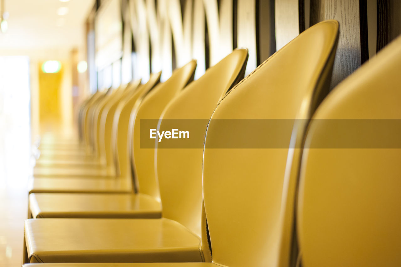 Empty yellow chairs arranged in row