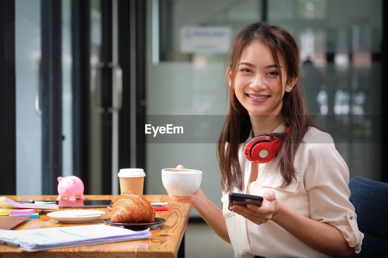 Portrait of smiling woman holding smart phone