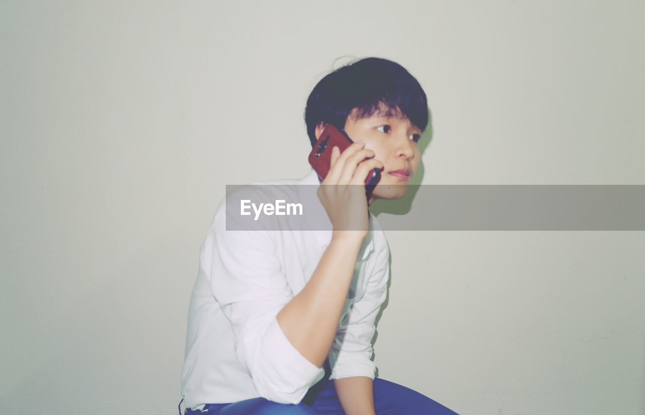 PORTRAIT OF BOY LOOKING AWAY AGAINST WALL