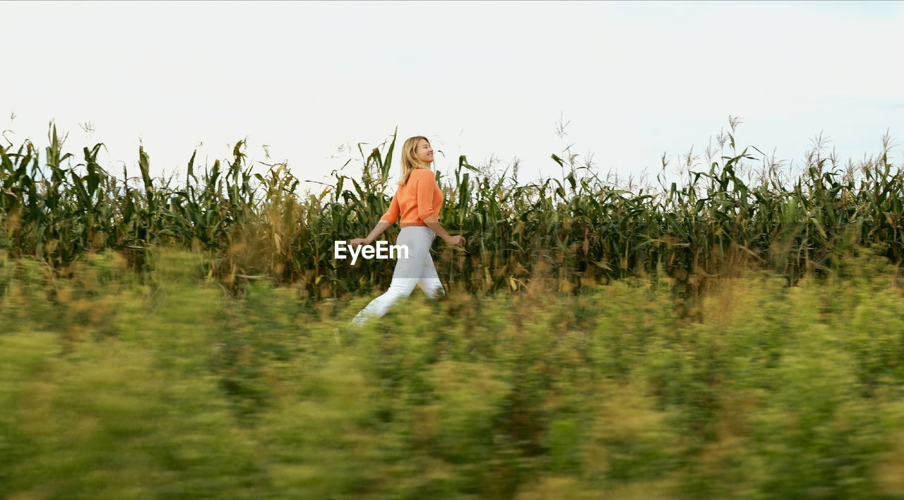 rear view of woman standing on field against sky