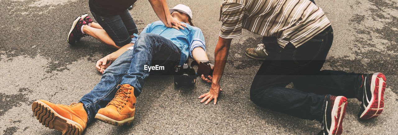 Man giving hands only cpr to patient lying on road