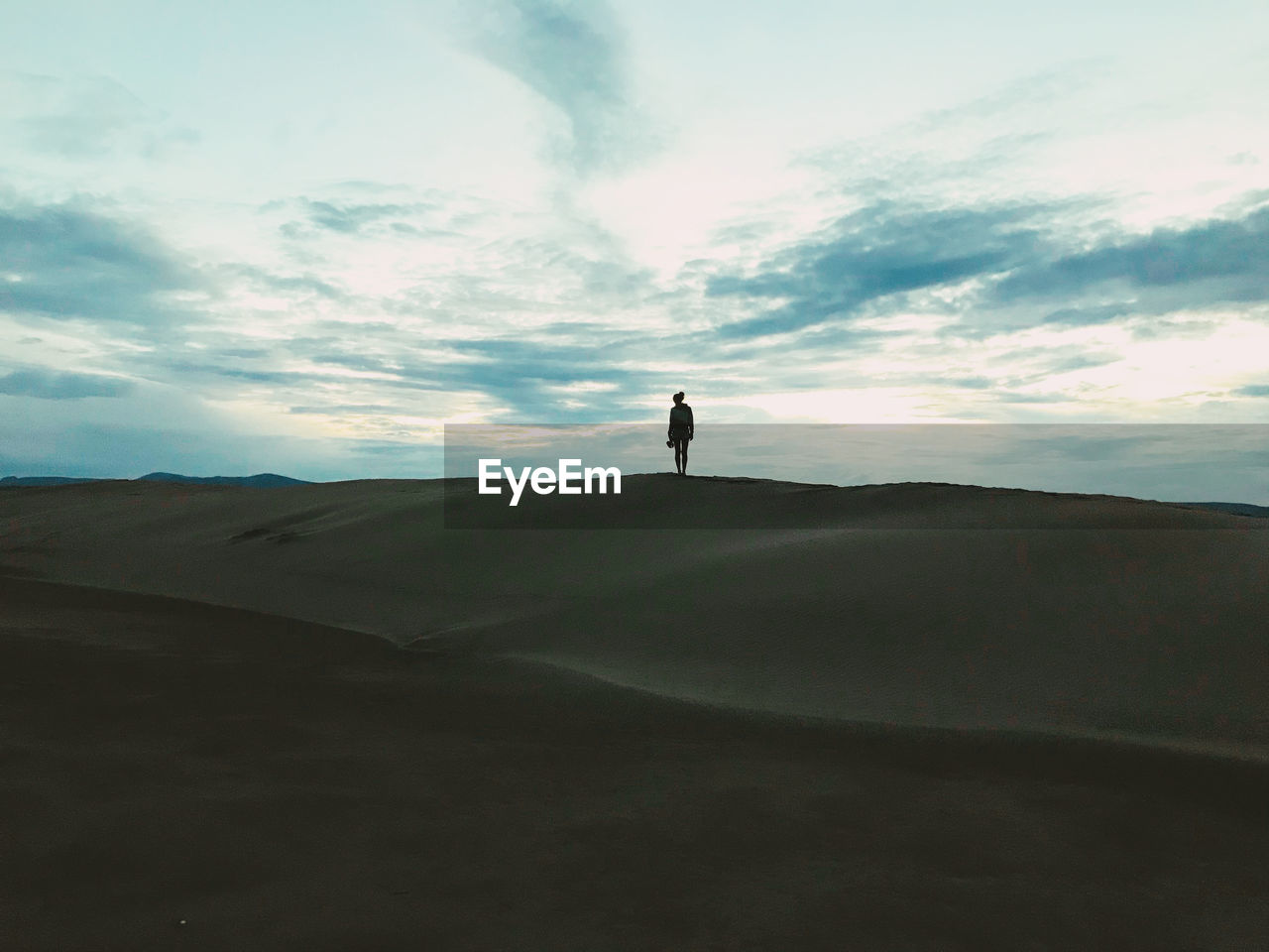 Silhouette standing on a sand dune at sunset 