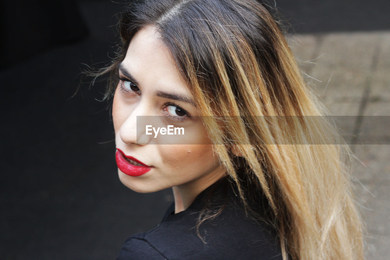 Close-up portrait of beautiful young woman standing on footpath