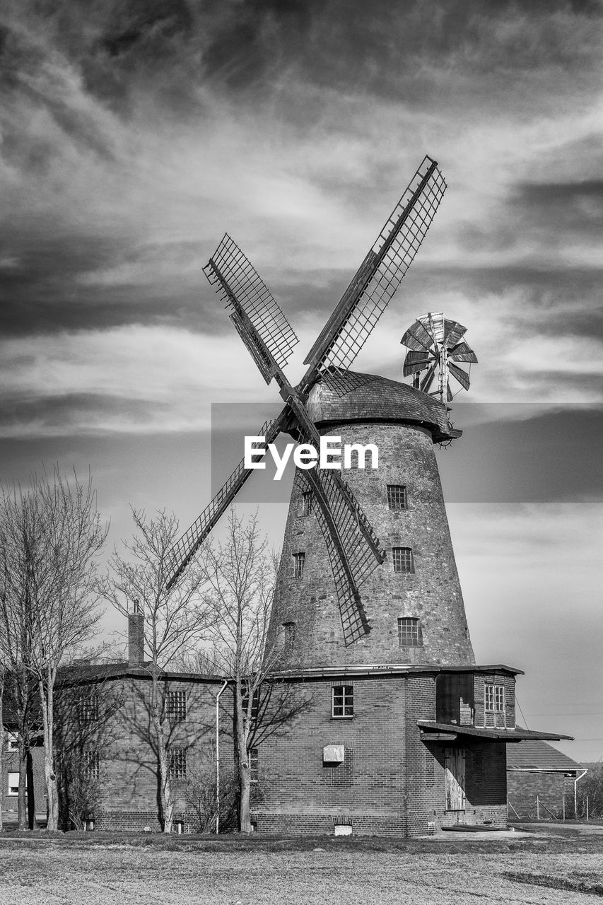 Traditional windmill on field against sky