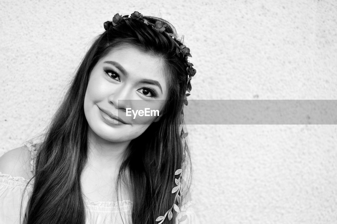 Portrait of beautiful young woman against wall