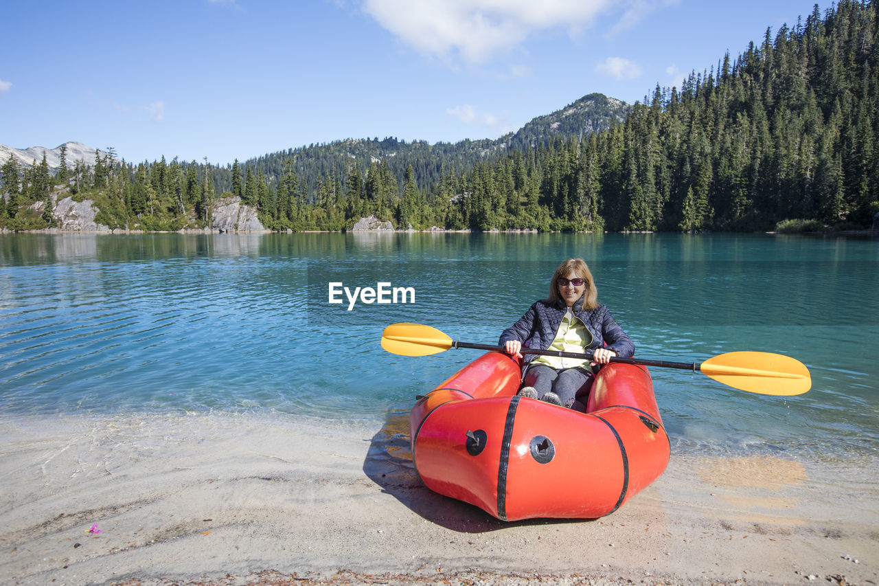 Retired woman enjoys paddling boat at remote lake.