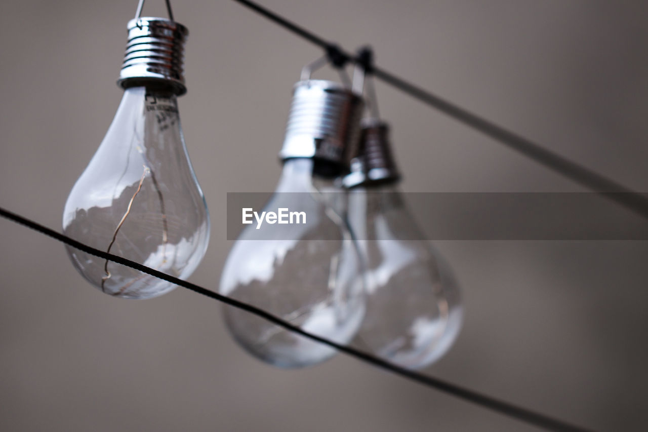 Low angle view of light bulbs hanging on cable