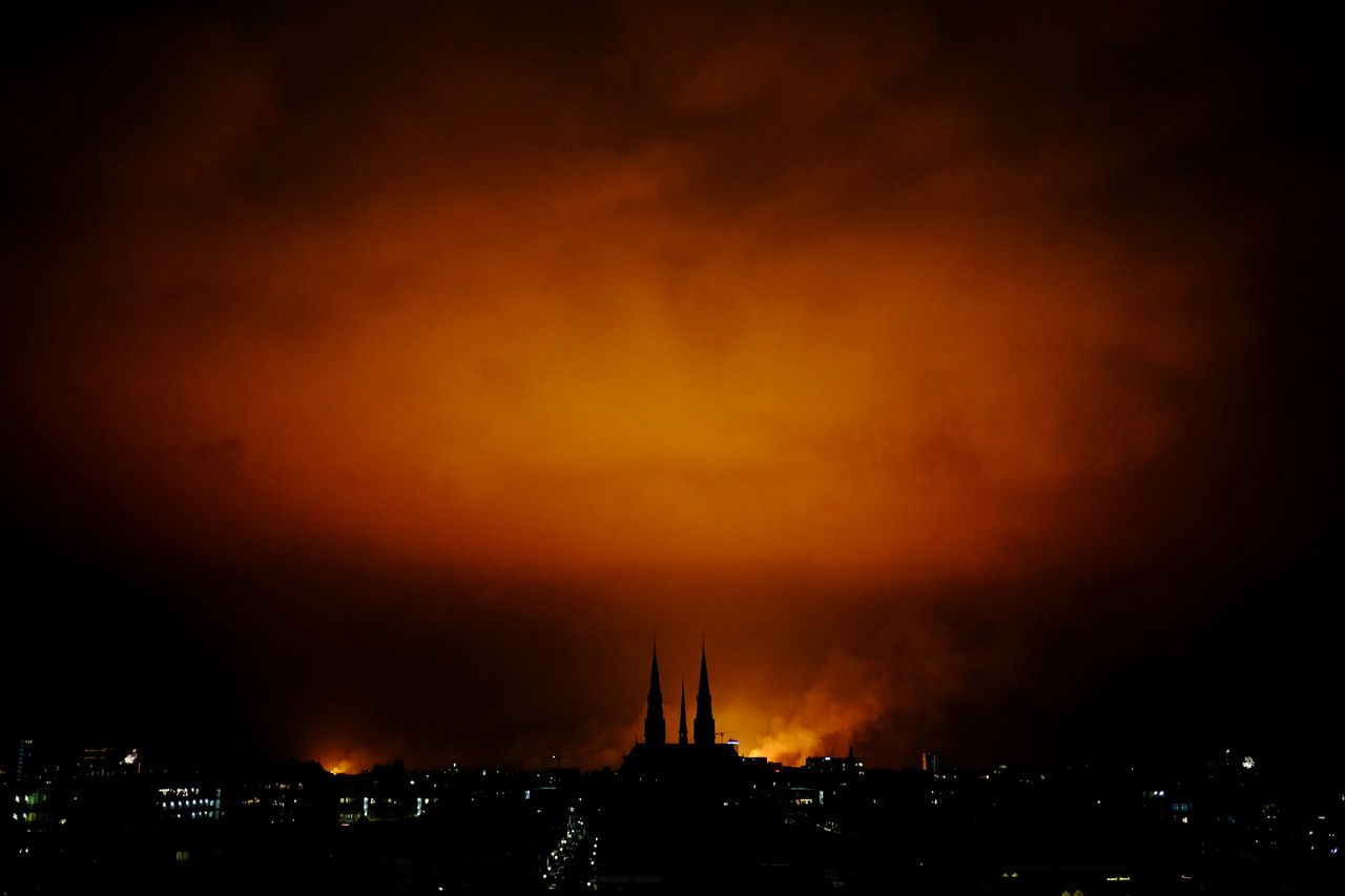 Silhouette buildings against cloudy sky at night