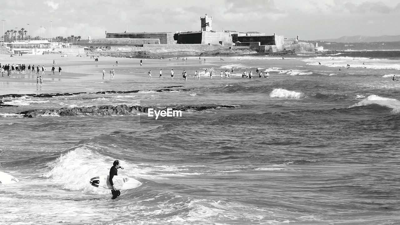 Man holding surfboard while standing in sea