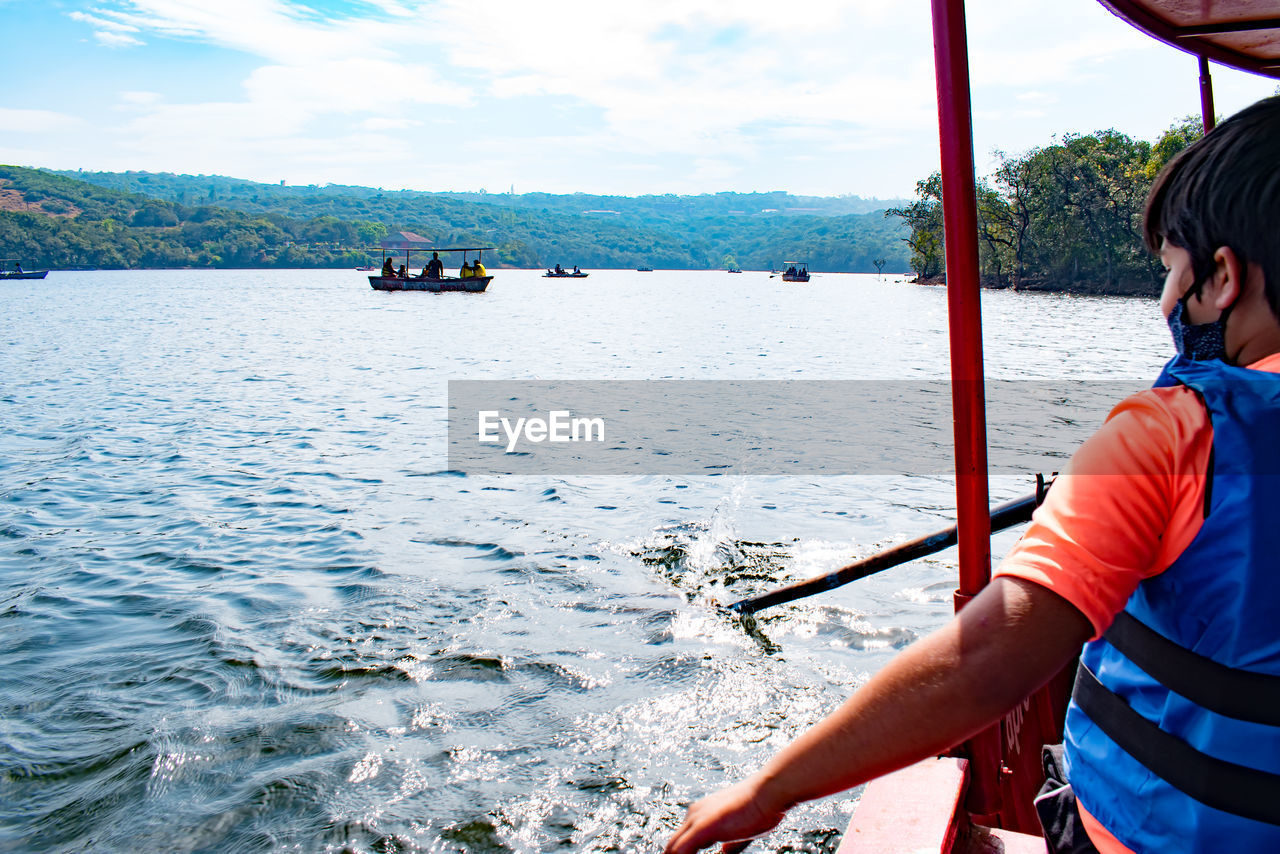 Rear view of boy sitting on a boat in lake 